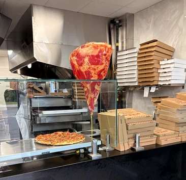 Pizza counter with a giant pizza slice sign and stacked pizza boxes